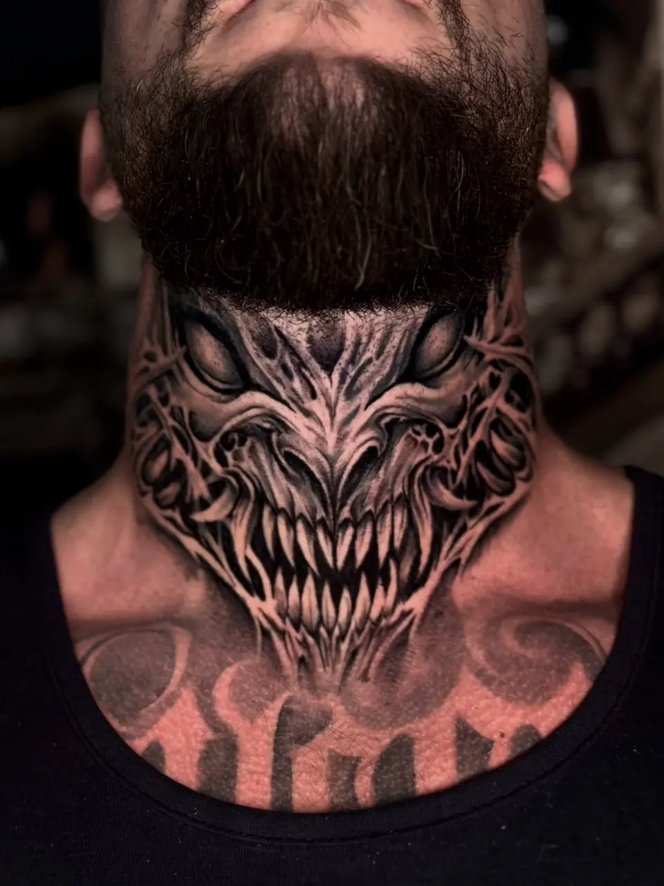 Criatura de dentes à mostra tatuada no pescoço